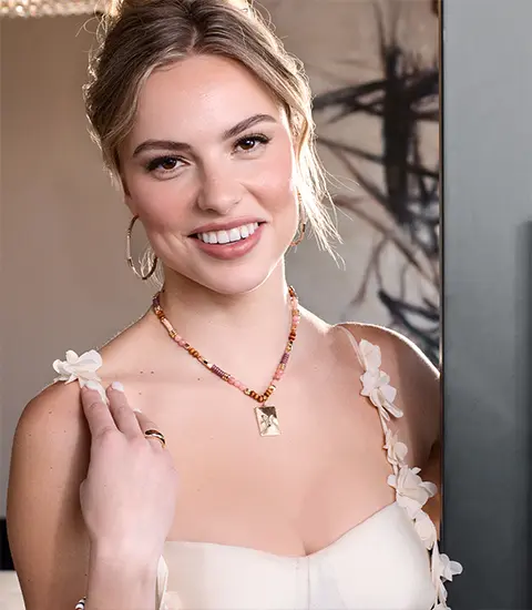 Model wearing Pink and orange feathered earrings, with color-matching necklace, wearing orange dress